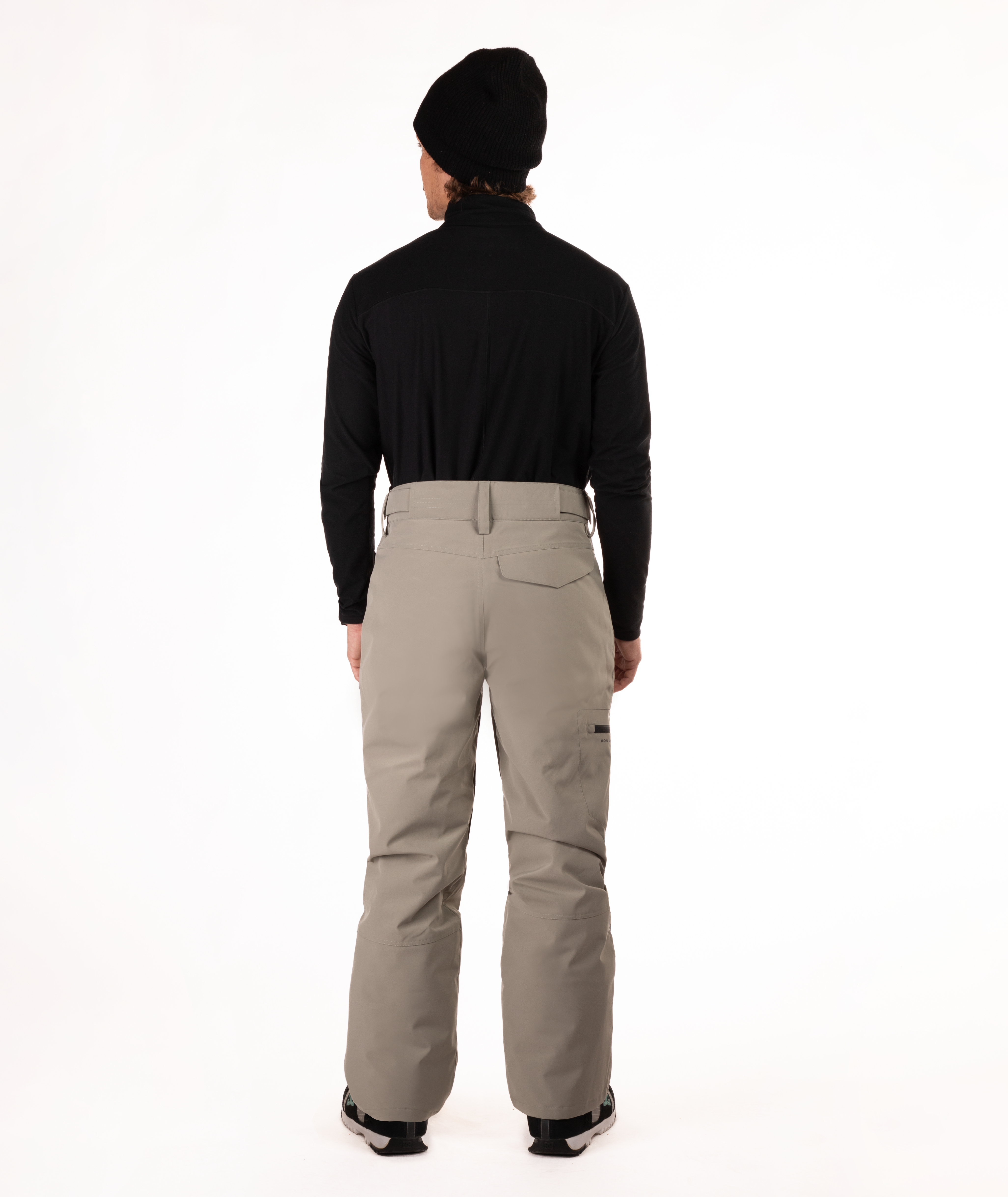back of Person wearing a black top and beige snow pants on a white background
