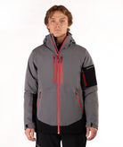 A man wearing a gray and black ski jacket with bright red zippers, standing against a plain white studio background.