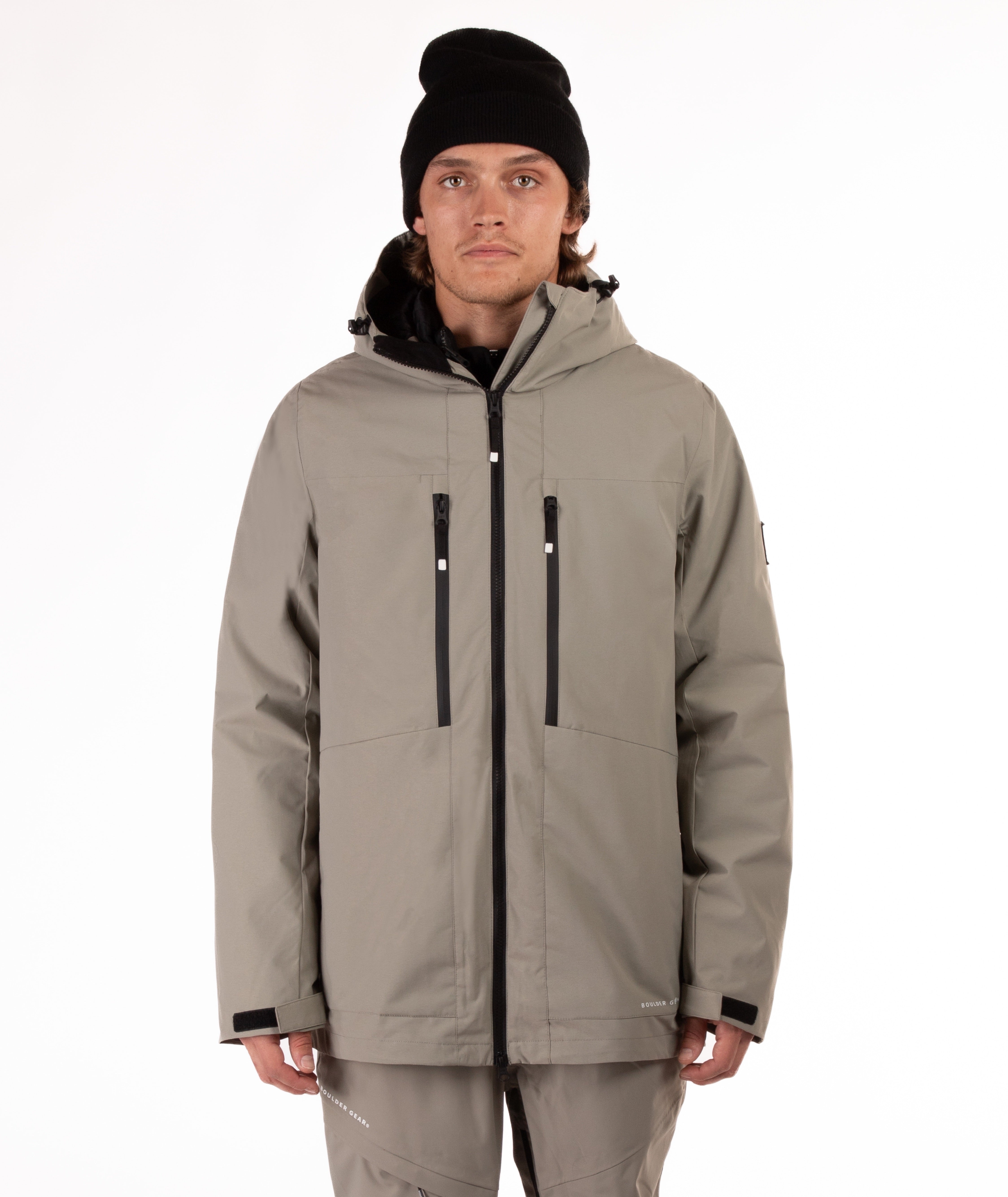 Person wearing a beige jacket with black zippers on a white background