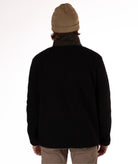 back of man wearing a black fleece jacket with a green collar on a white background
