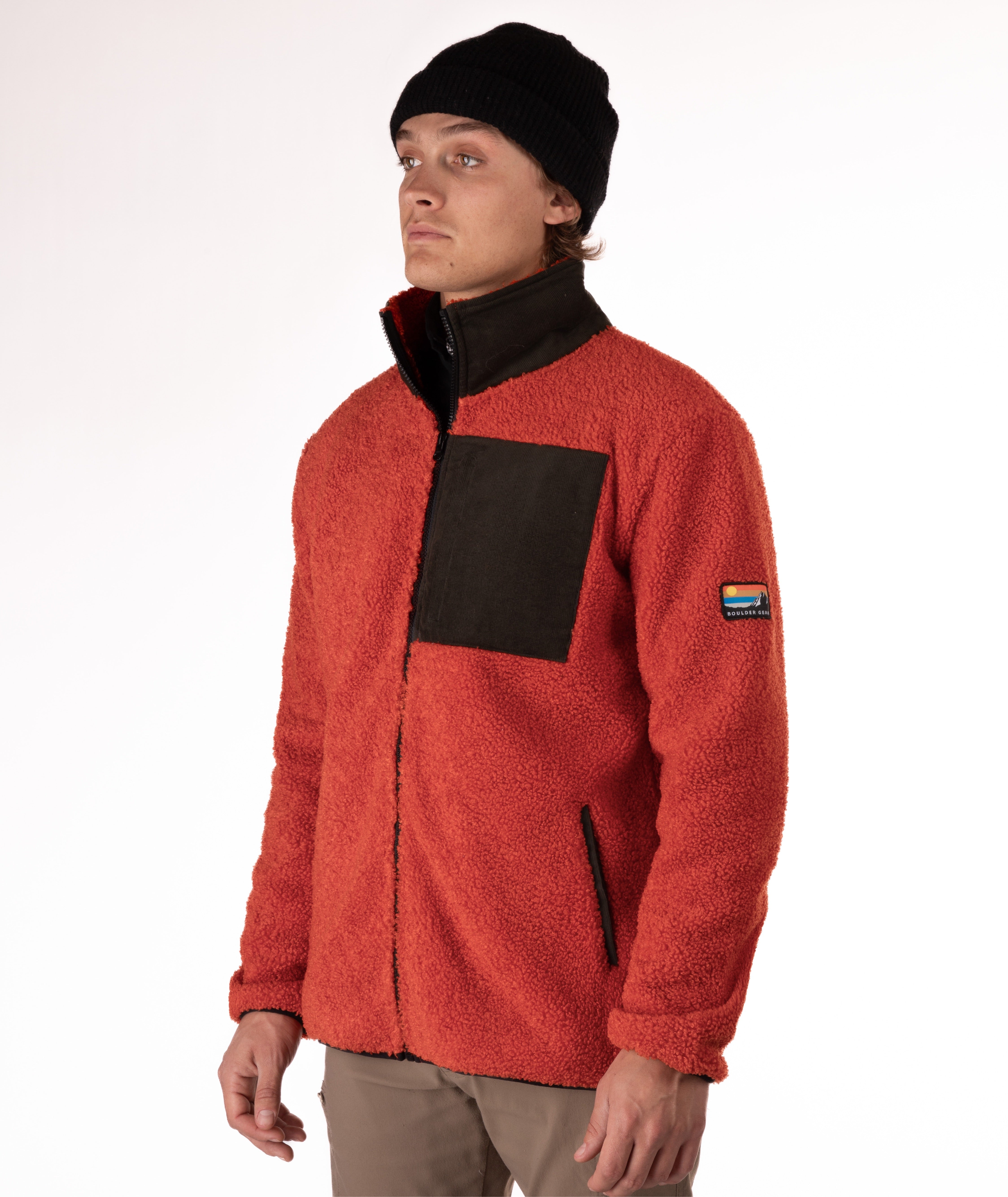 man wearing an orange fleece jacket with green chest pocket and collar on white background