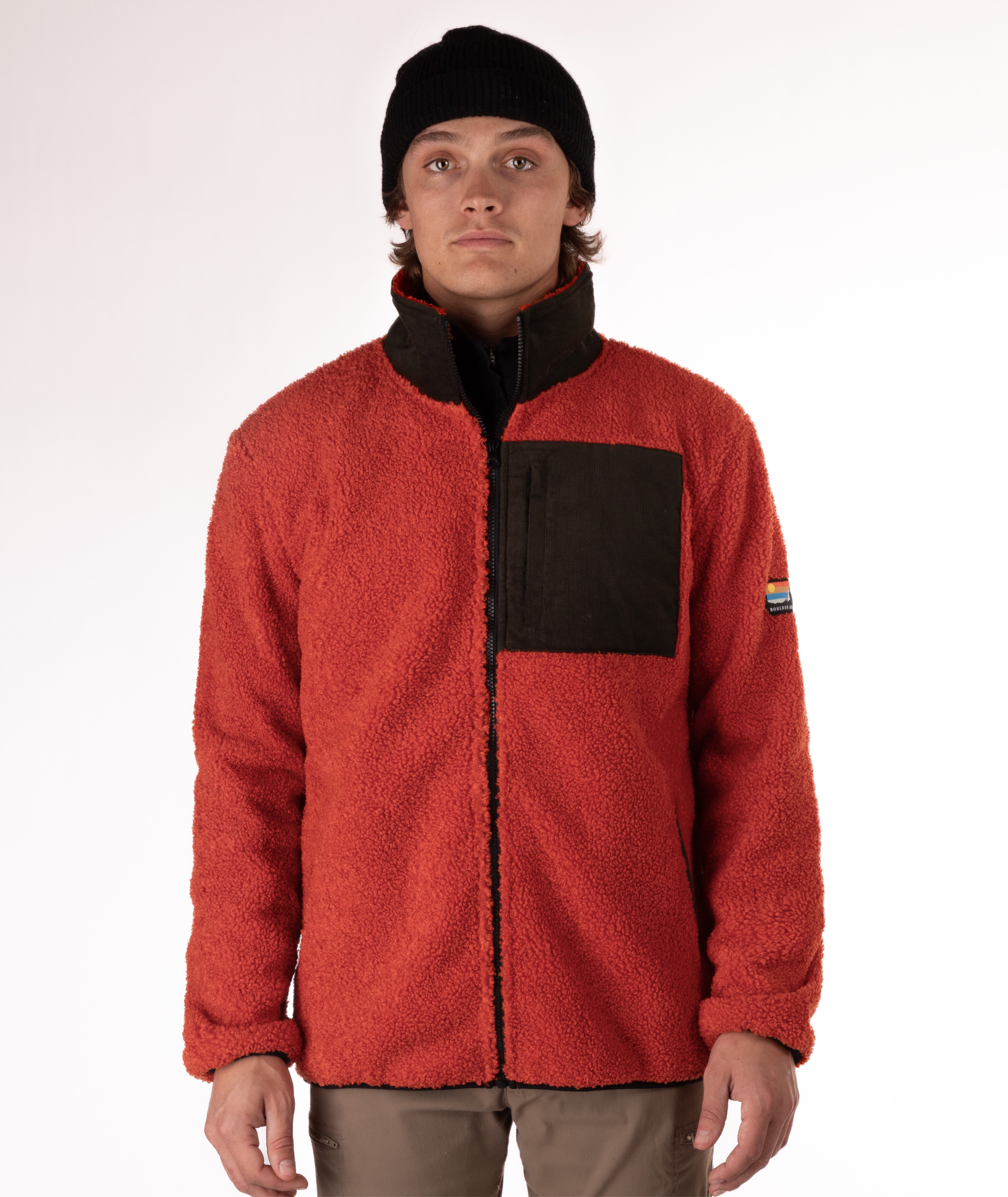 man wearing an orange fleece jacket with green chest pocket and collar on white background