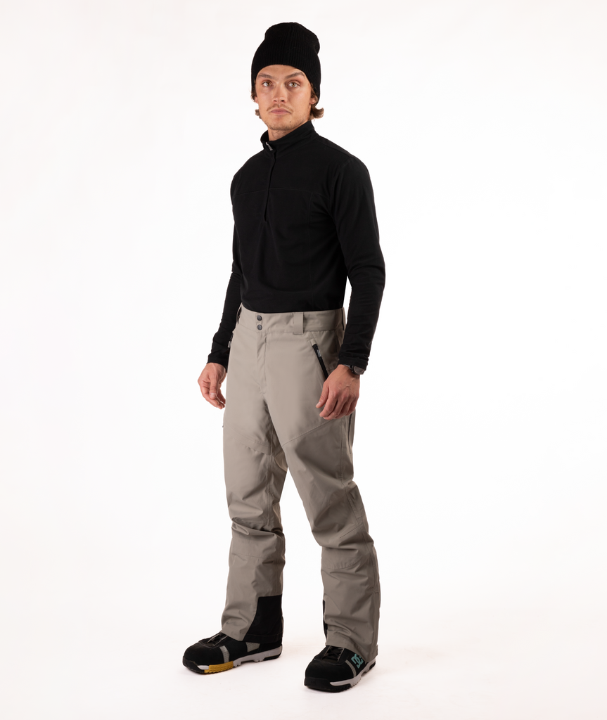 Person wearing a black top and beige snow pants on a white background
