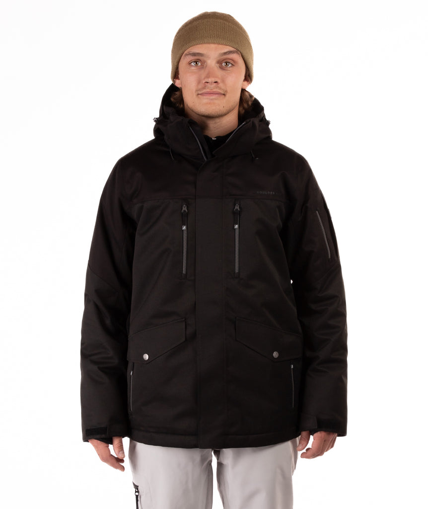 Person wearing a black jacket with chest pocket zippers on a white background