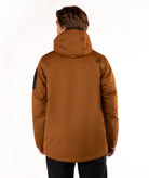 A person viewed from the back wearing a hooded insulated jacket in a warm camel-brown color, with black pants, against a plain white studio background.