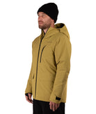 A man wearing a hooded insulated jacket in a muted mustard yellow color, paired with a black beanie and black pants, standing against a solid white background.