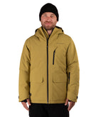 A man wearing a hooded insulated jacket in a muted mustard yellow color, paired with a black beanie and black pants, standing against a solid white background.