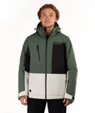 A man wearing a color-blocked ski jacket in dark green, black, and light green against a plain white background.