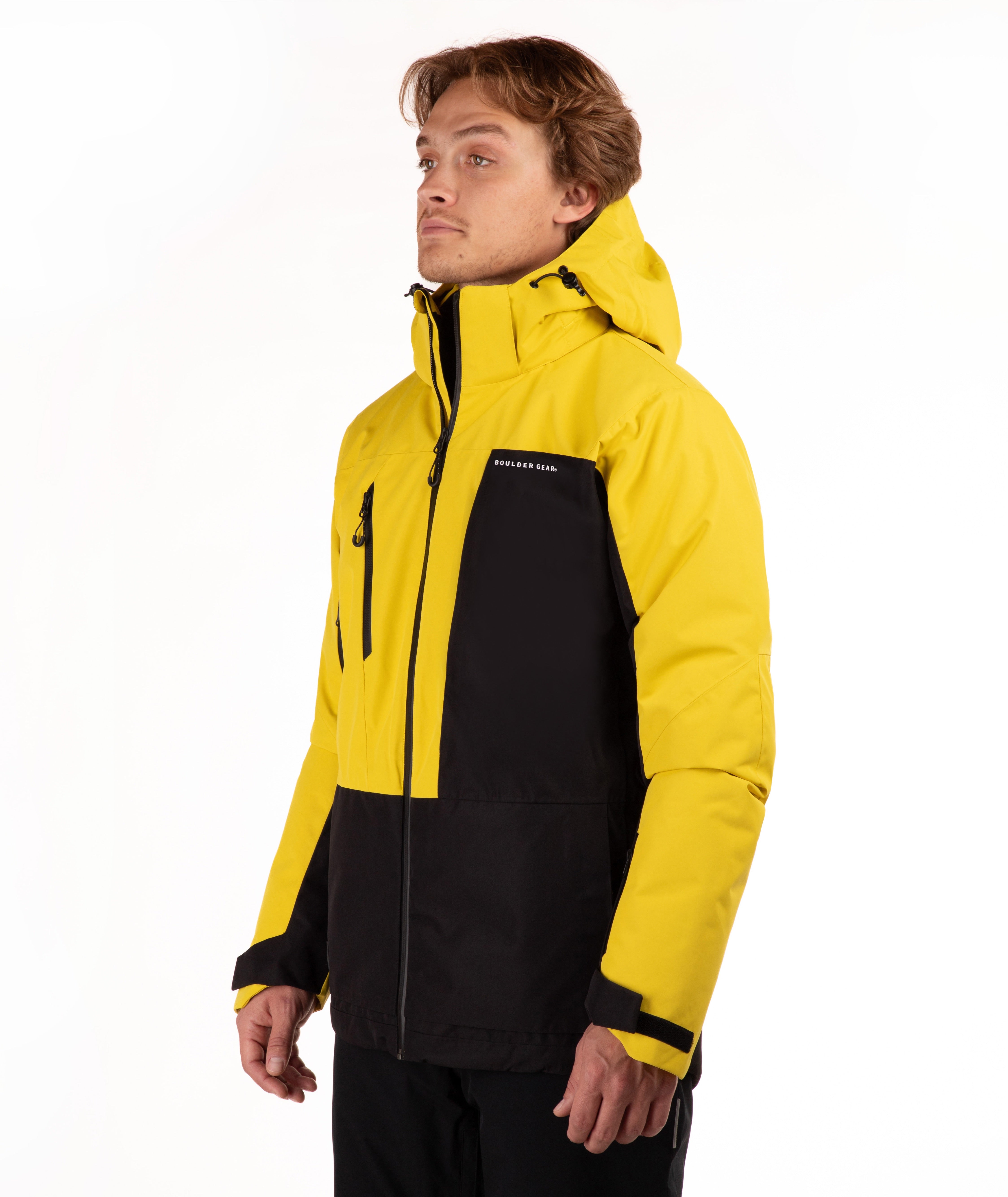 A man wearing a bright yellow and black technical outdoor jacket with a full front zipper, zippered chest pocket, and adjustable hood, photographed against a clean white studio background.