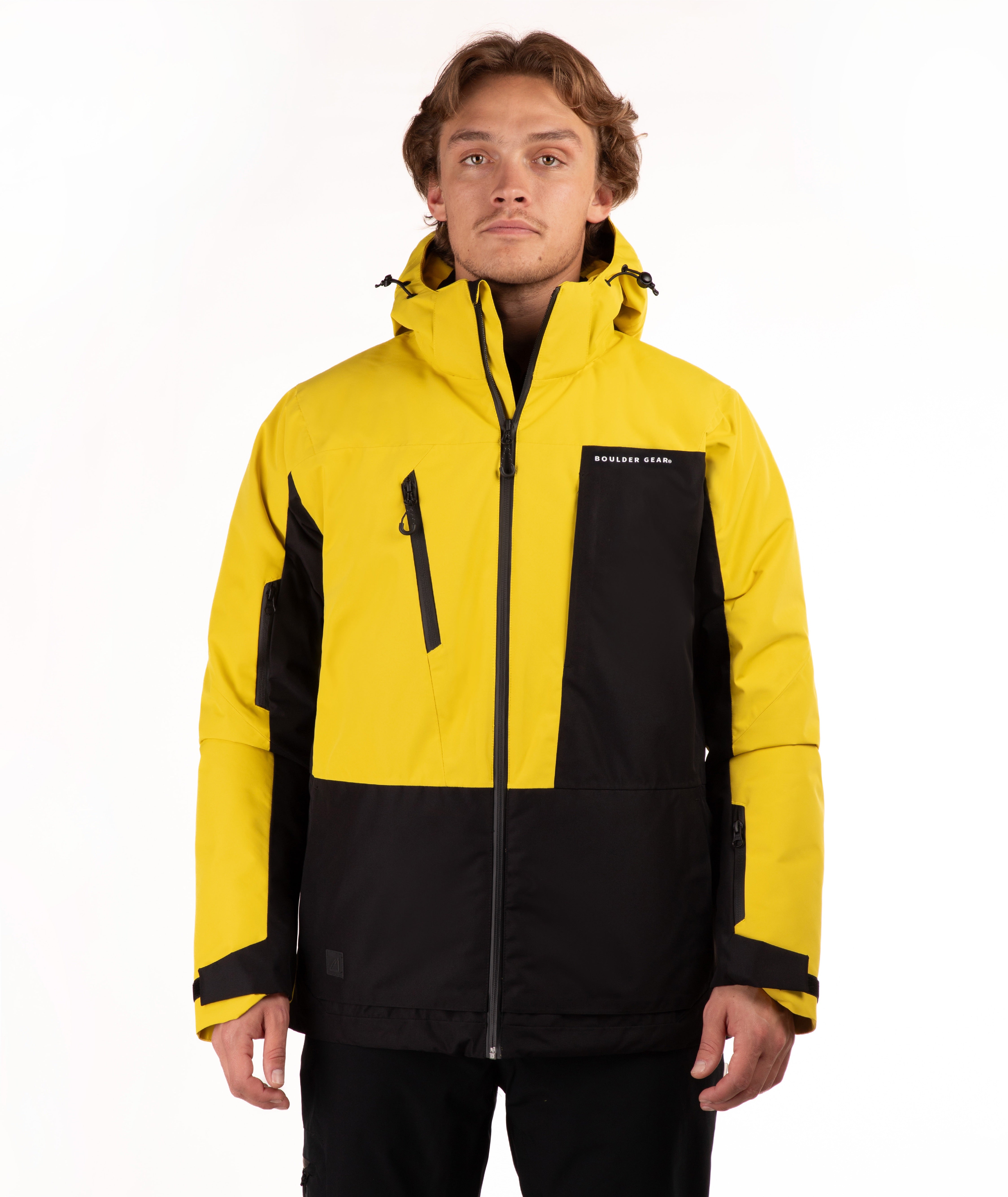 A man wearing a bright yellow and black technical outdoor jacket with a full front zipper, zippered chest pocket, and adjustable hood, photographed against a clean white studio background.