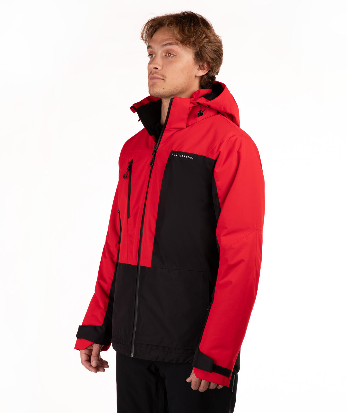 A man wearing a red and black color-blocked ski jacket with a full-zip front and hood, standing against a plain white studio background.
