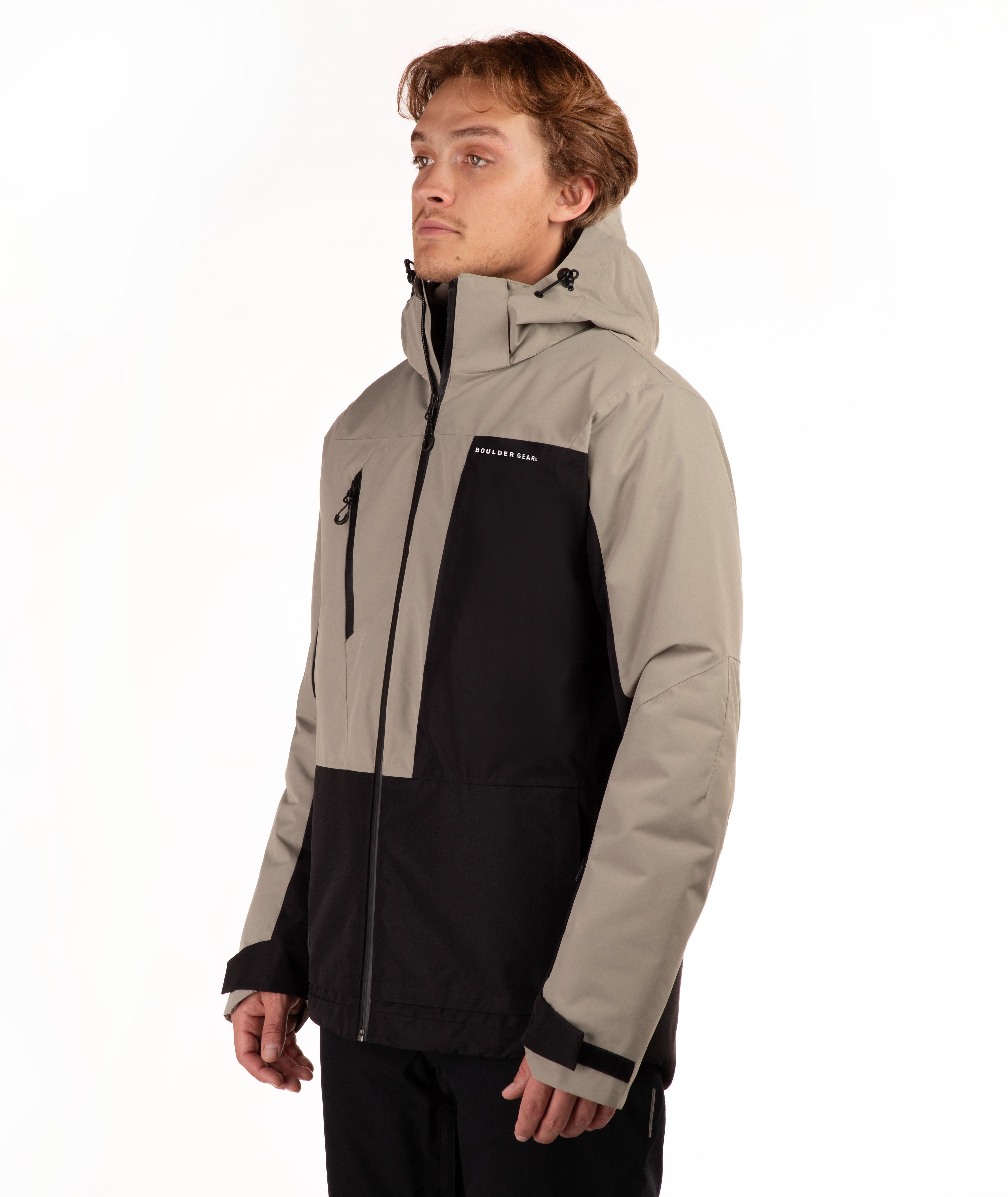 A man wearing a color-blocked ski jacket in beige and black, featuring a full-zip front, a vertical zip pocket on the chest, shot against a plain white background.