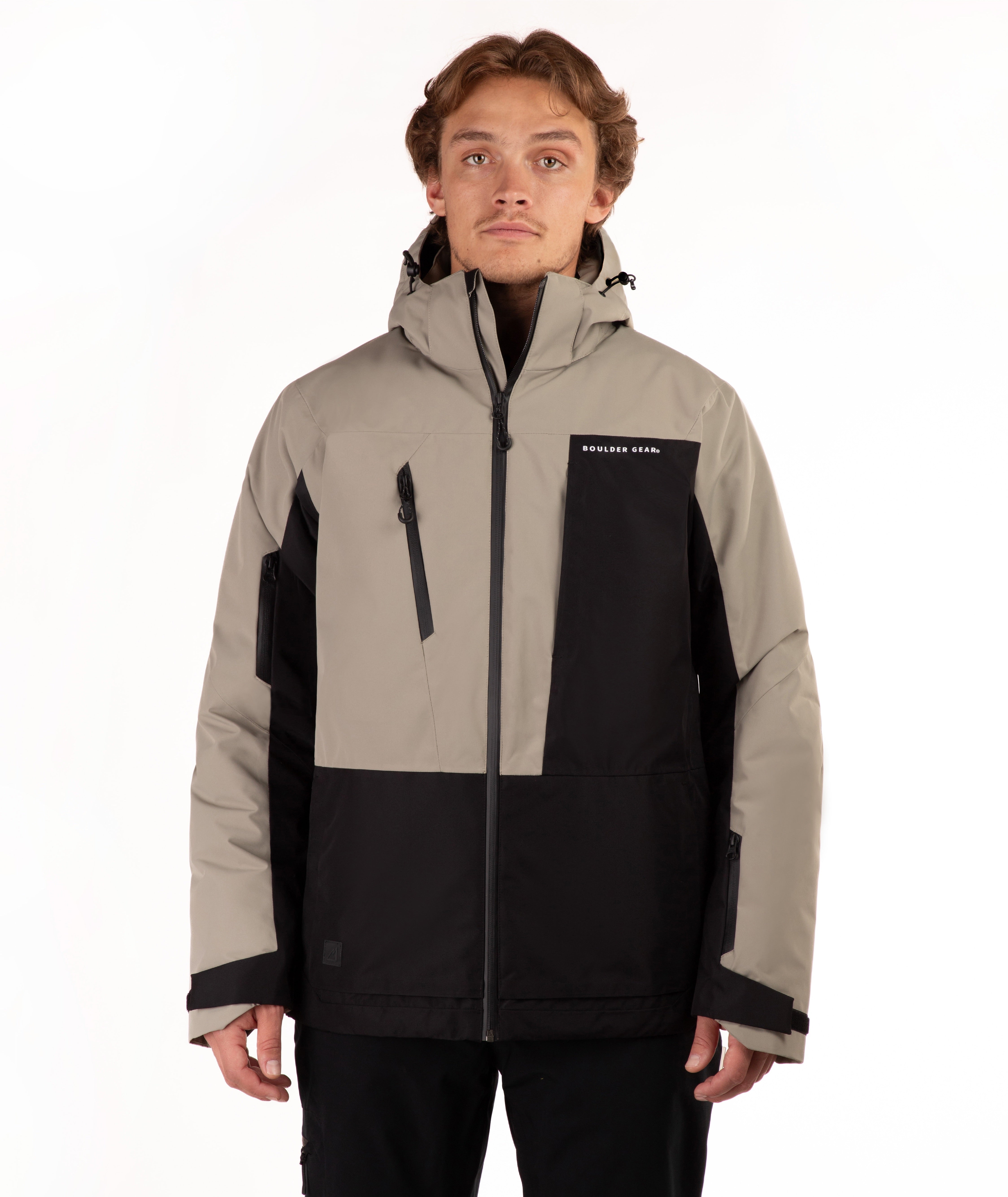 A man wearing a color-blocked ski jacket in beige and black, featuring a full-zip front, a vertical zip pocket on the chest, shot against a plain white background.
