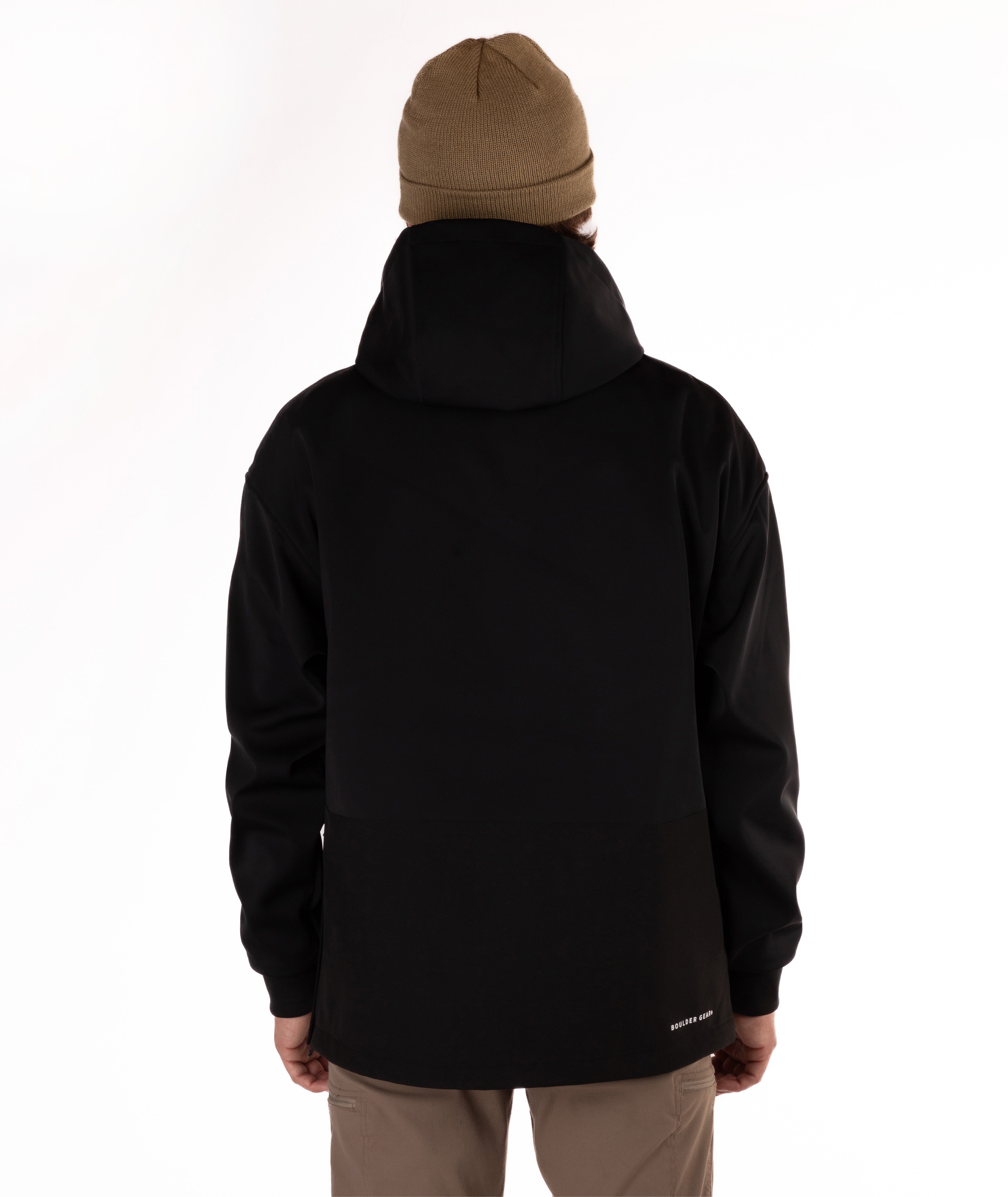 A person shown from the back wearing a black hooded jacket, a tan beanie, and tan pants against a plain white studio background.