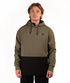 A man wearing a color-blocked pullover hoodie with an olive green upper section and a black lower section, standing against a plain white background.