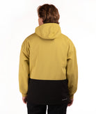 A person shown from the back wearing a hooded jacket with a two-tone design, featuring a mustard yellow upper section and a black lower section, against a plain white background.