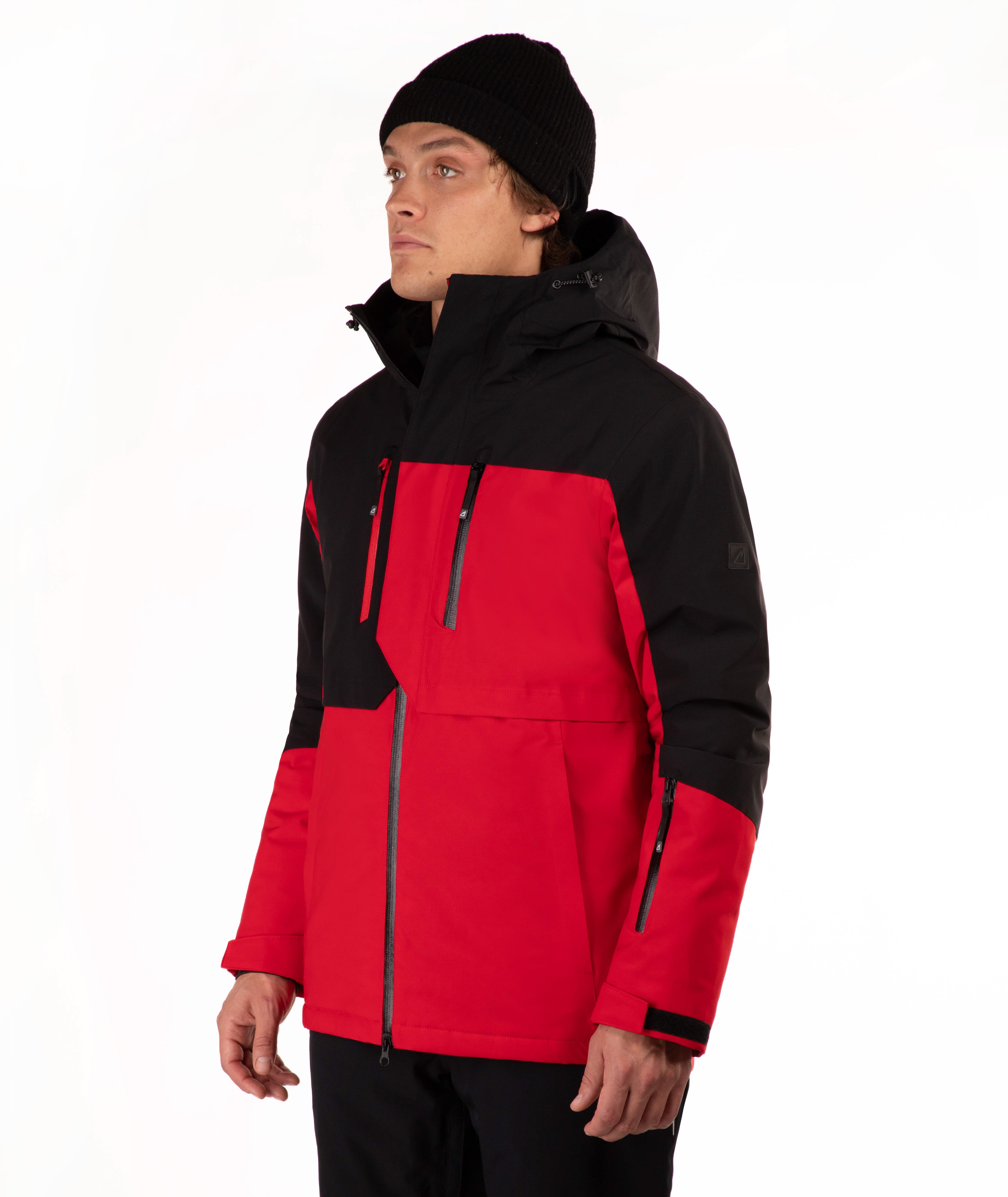 A model wearing a red and black color-blocked ski jacket with a black beanie, photographed against a clean white studio background.