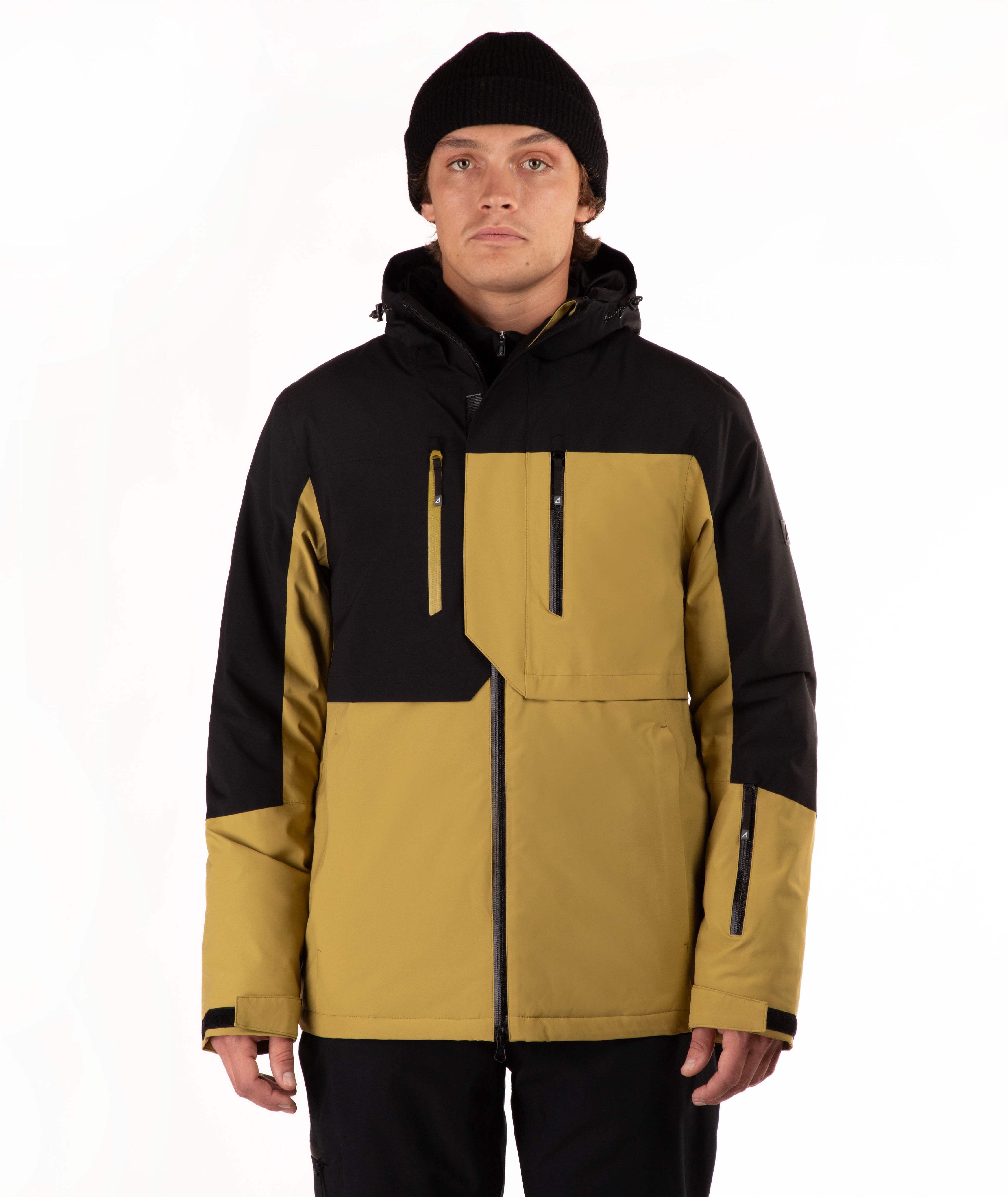 A man wearing a color-blocked ski jacket in black and mustard yellow, paired with a black beanie, photographed against a plain white studio background.