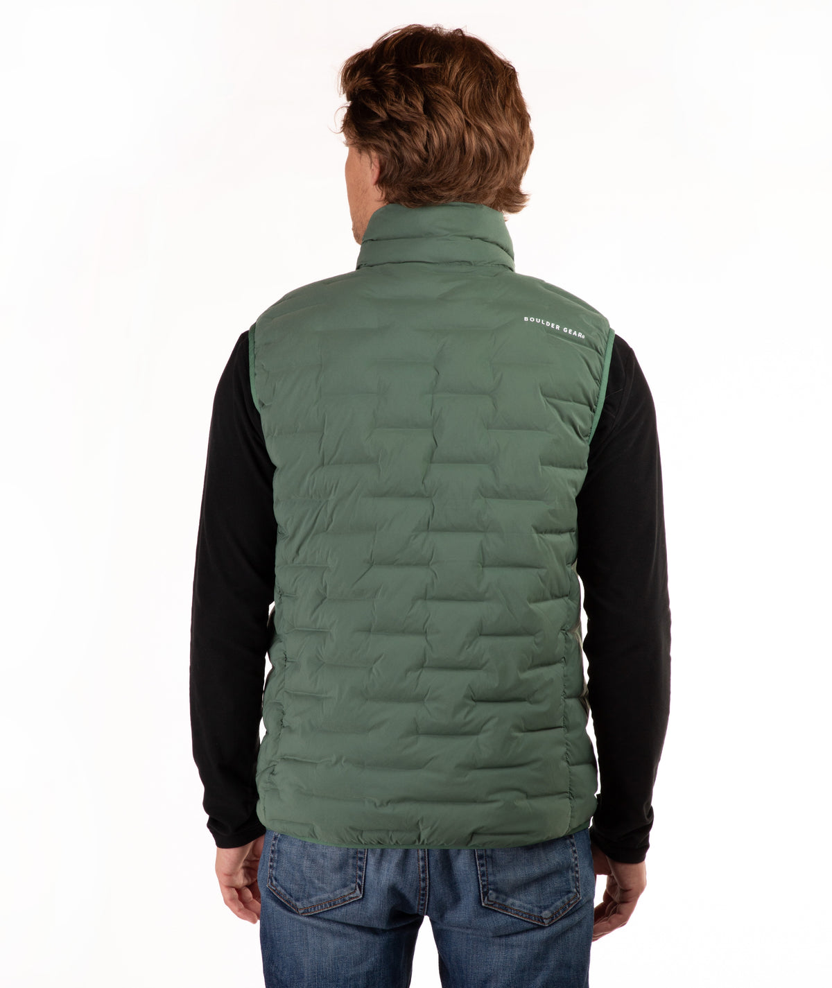 A man viewed from behind wearing a  green quilted puffer vest over a black long-sleeve shirt and blue jeans, against a plain white background.