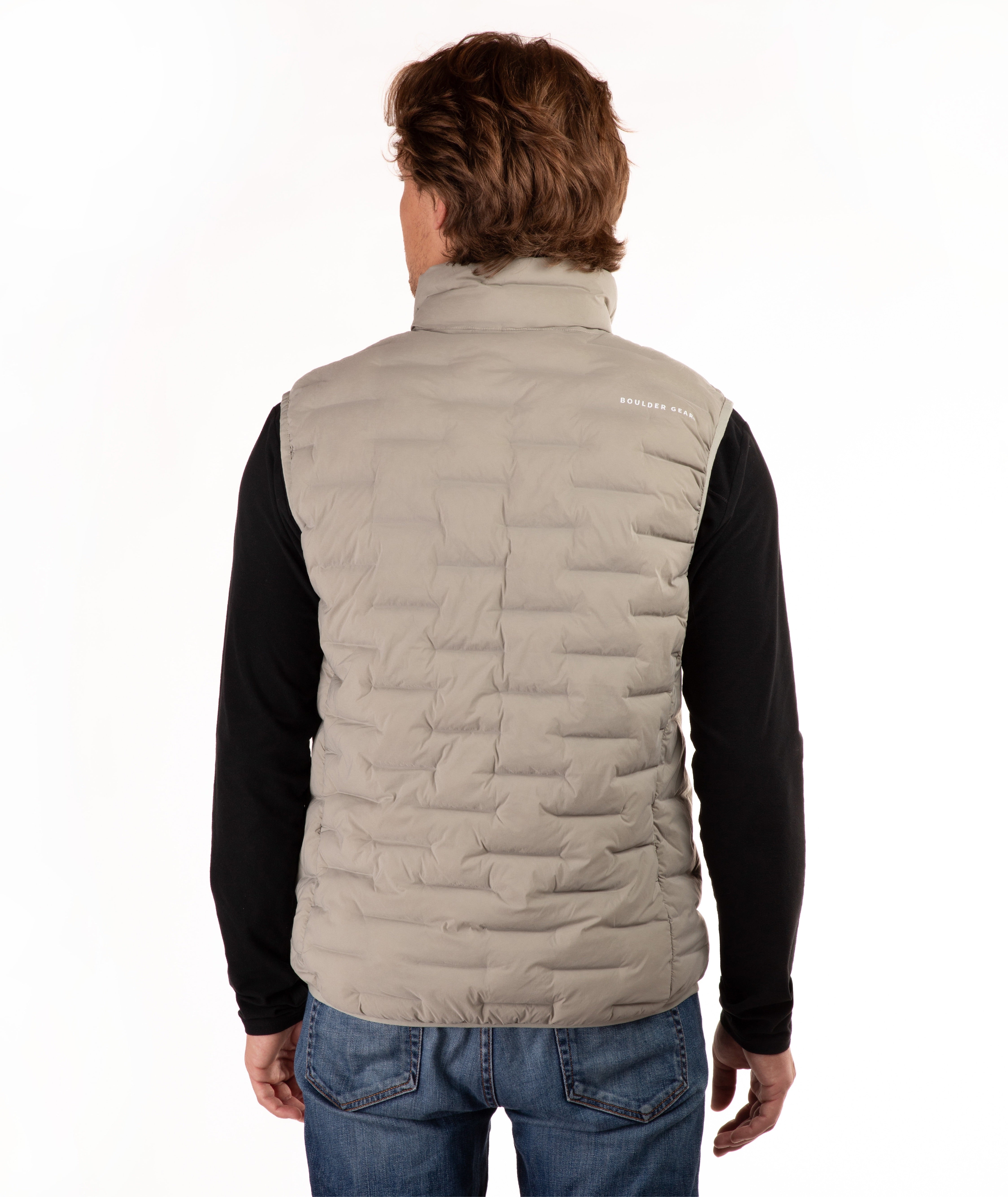 A man viewed from the back wearing a light beige puffer vest over a black long-sleeve shirt and blue jeans, against a plain white background.