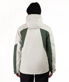 A person shown from the back wearing a hooded jacket with a light green body and dark green shoulder and sleeve panels, along with a black beanie and dark pants, against a plain white studio background.
