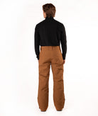 A man viewed from behind wearing a black long-sleeve shirt and brown pants, standing against a plain white studio background.