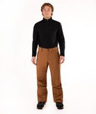 A man modeling a black long-sleeve quarter-zip fleece and brown ski pants against a solid white studio background.