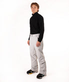 A man modeling a black long-sleeve quarter-zip pullover and light gray snow pants against a plain white studio background.