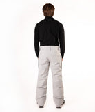 A model shown from the back wearing a black long-sleeve turtleneck top and light gray snow pants against a white studio background.
