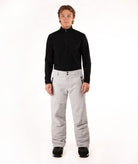 A man modeling a black long-sleeve quarter-zip pullover and light gray snow pants against a plain white studio background.