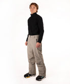 A man modeling a black long-sleeve quarter-zip fleece and beige ski pants against a white studio background.