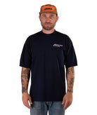 Man wearing a navy t-shirt with a logo and a brown cap on a white background