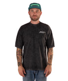 Man wearing a faded black t-shirt with a logo and a green cap on a white background