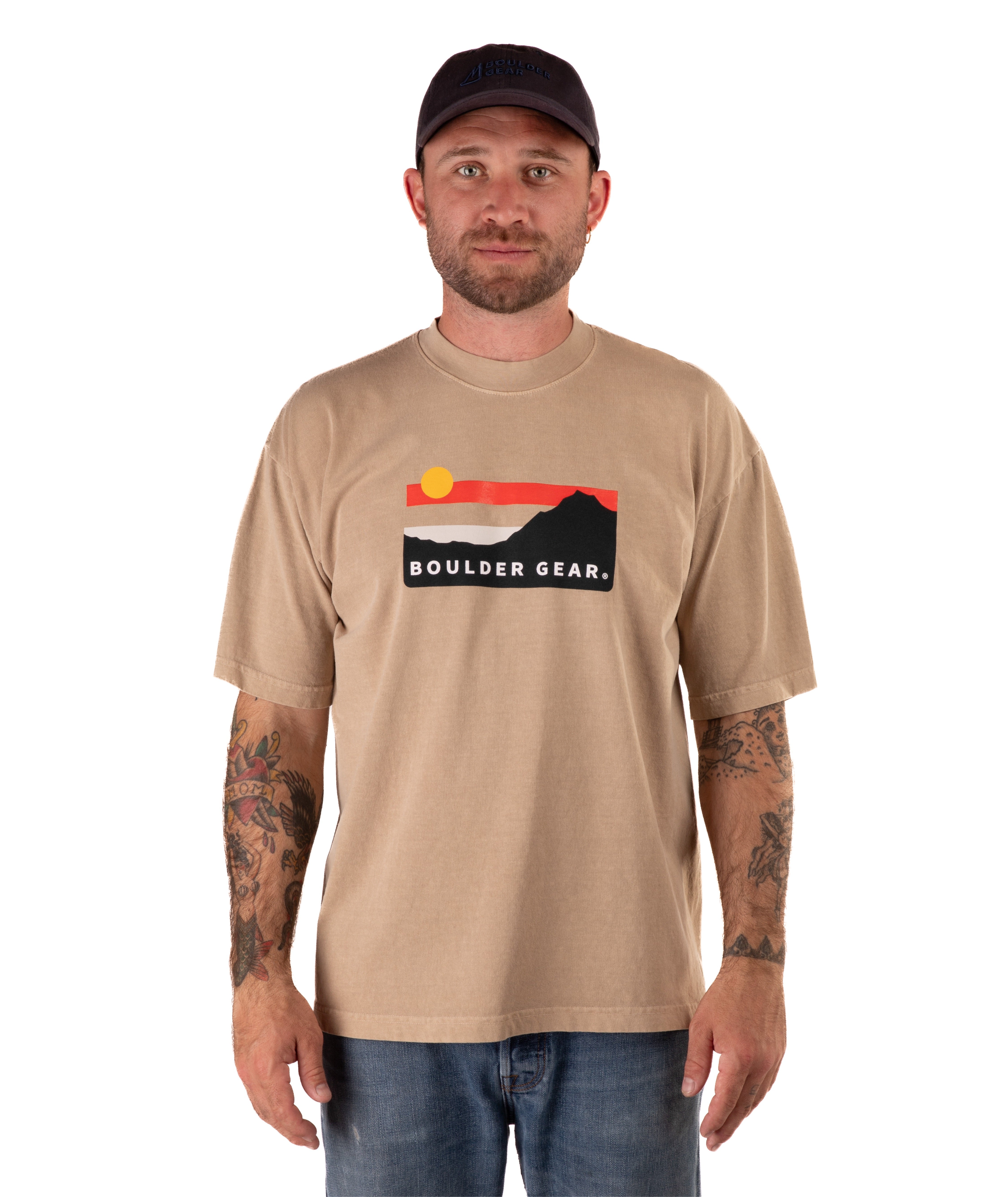 Man wearing a beige t-shirt with a logo and text, standing against a white background