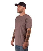 man in a brown shirt with black text and a black hat on a white background