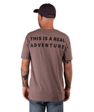 back of a man in a brown shirt with black text and a black hat on a white background