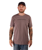 man in a brown shirt with black text and a black hat on a white background