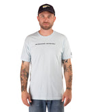 Man wearing a light blue t-shirt with text and a black cap on a white background