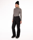 Person wearing a gray long-sleeve top and black snow pants on a white background