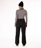 back of person wearing a gray long-sleeve top and black snow pants on a white background