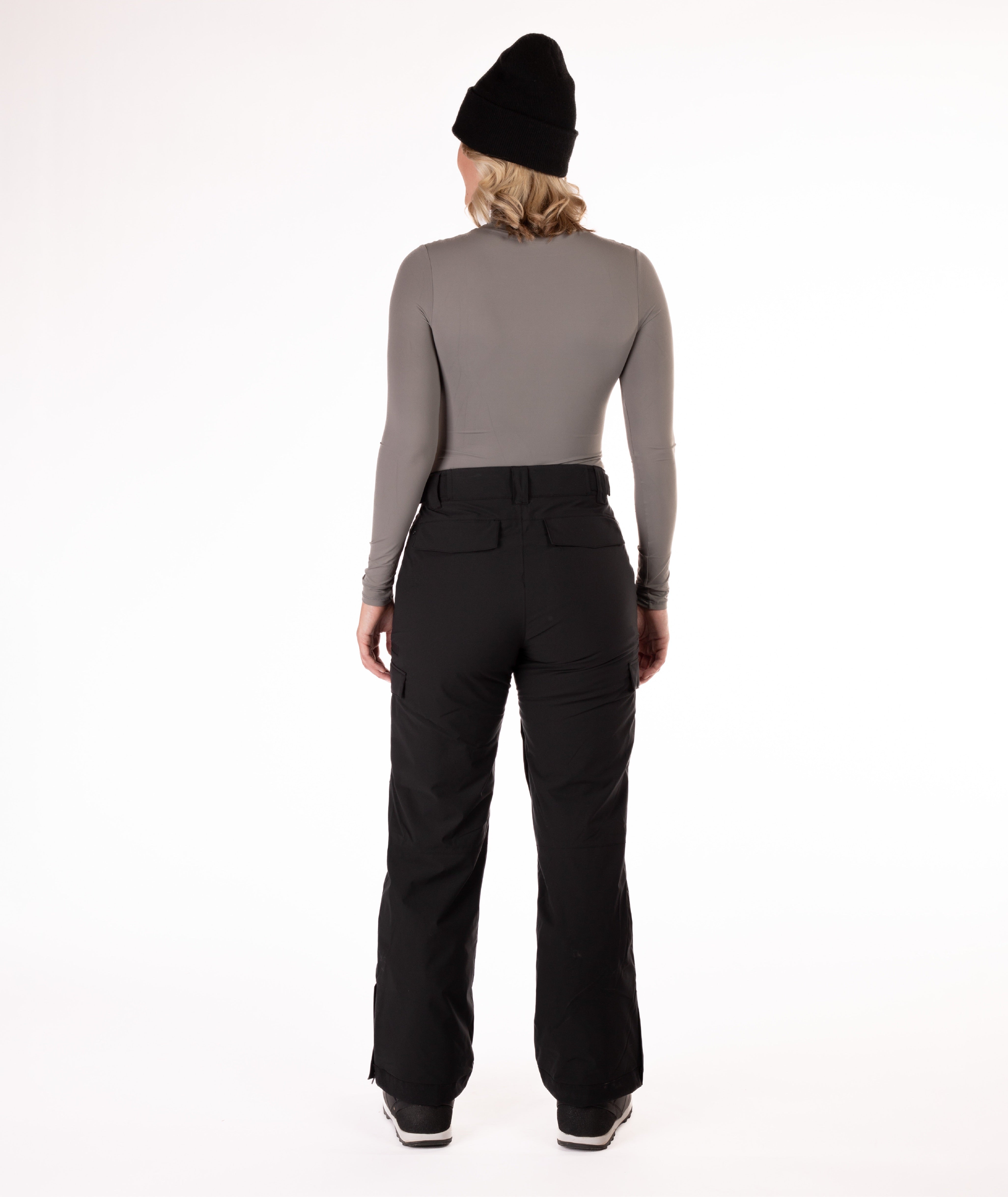 back of person wearing a gray long-sleeve top and black snow pants on a white background
