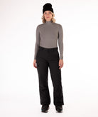 Person wearing a gray long-sleeve top and black snow pants on a white background