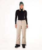 Person wearing a black long-sleeve top and beige snow pants on a white background