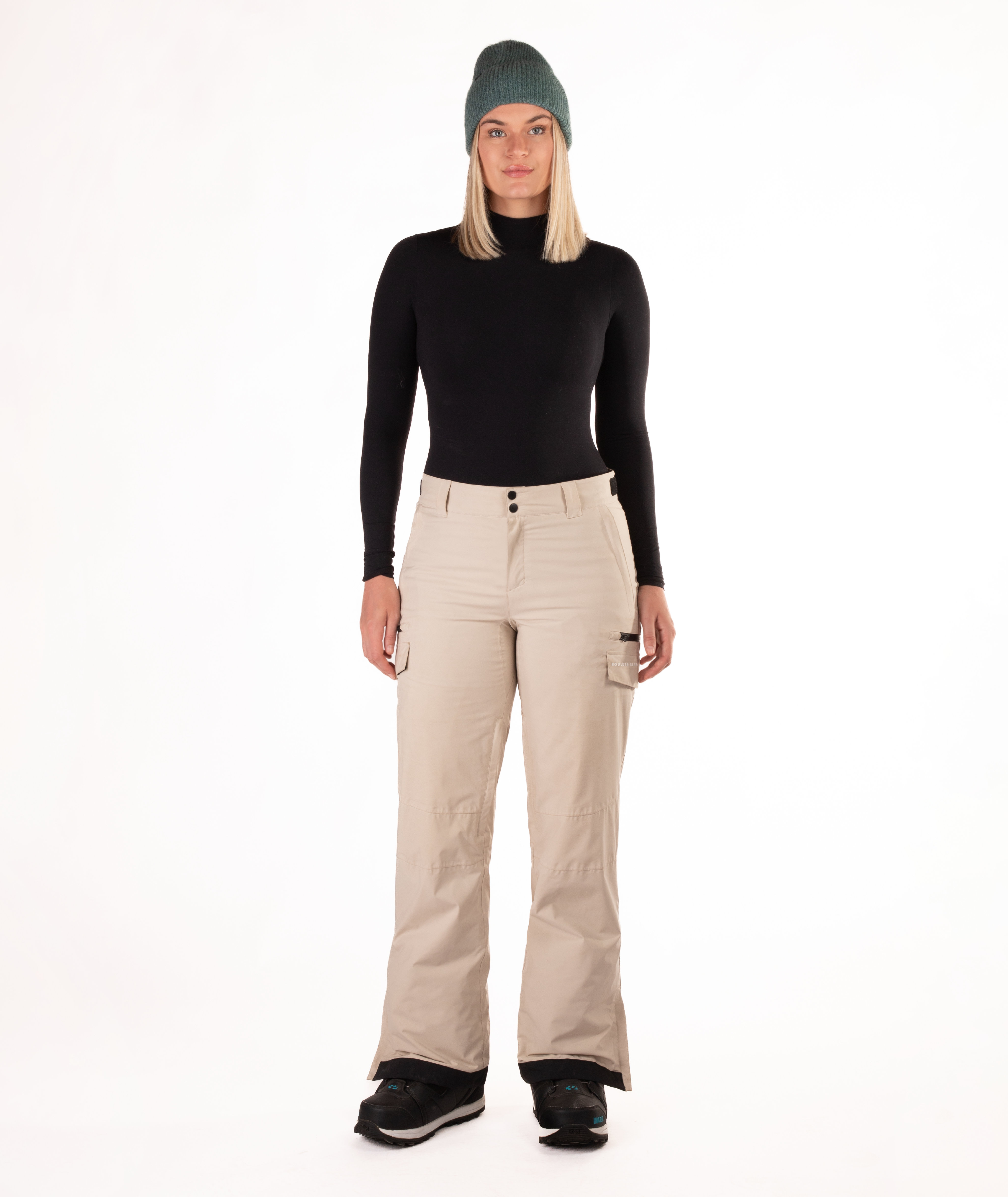 Person wearing a black long-sleeve top and beige snow pants on a white background