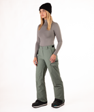 Person wearing a gray long-sleeve top and green snow pants on a white background