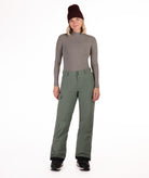 Person wearing a gray long-sleeve top and green snow pants on a white background