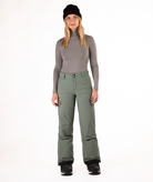 Person wearing a gray long-sleeve top and green snow pants on a white background