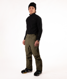Person wearing a black shirt and green snow pants on a white background