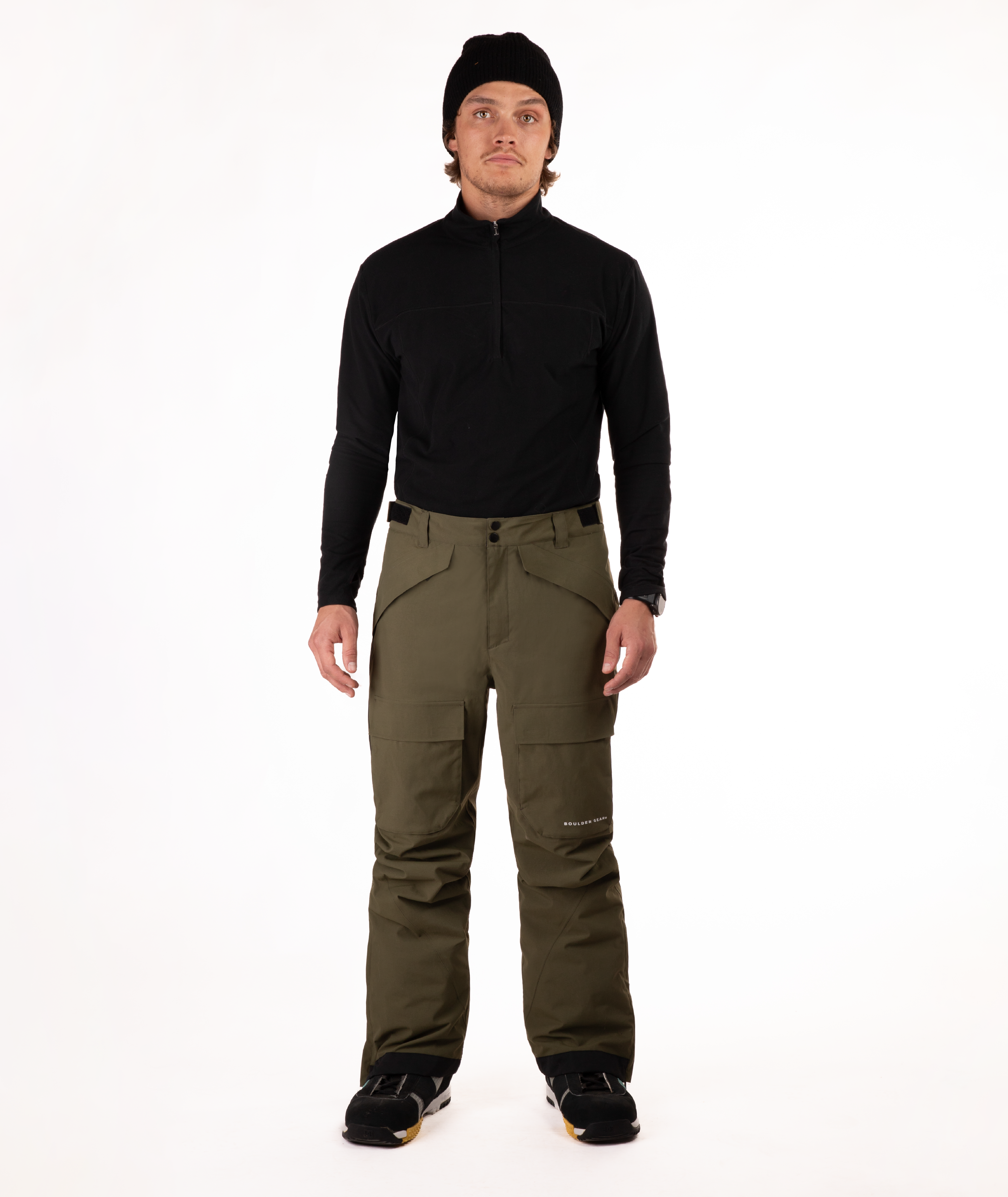 Person wearing a black shirt and green snow pants on a white background