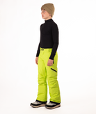 youth boy wearing a black long-sleeve shirt and bright green snow pants on a white background